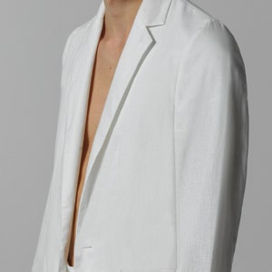 May include: A white linen blazer with a notched collar and a single button closure. The blazer has a pocket on the left side and a smooth, textured fabric.