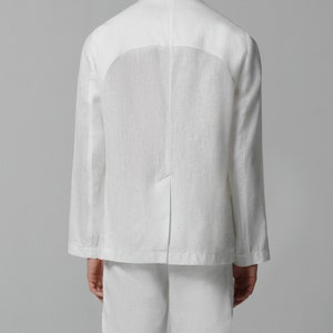 May include: A white linen blazer with a relaxed fit. The blazer has a single button closure and a welt pocket on the back.