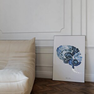 May include: A framed watercolor painting of a blue and gray human brain. The brain is depicted in profile, with the left side of the brain facing the viewer. The painting is on a white background and has a simple black frame.