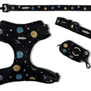 May include: A black dog harness, leash, collar, and poop bag holder with a space-themed print featuring planets, stars, and paw prints. The text "pouchdpo" is printed on the items.