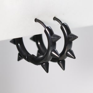 May include: A pair of black hoop earrings with sharp, pointed spikes around the edges.