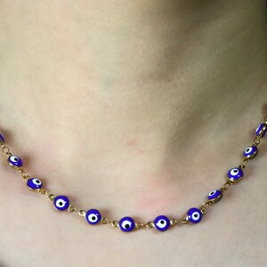May include: A gold chain necklace with blue and white evil eye charms.