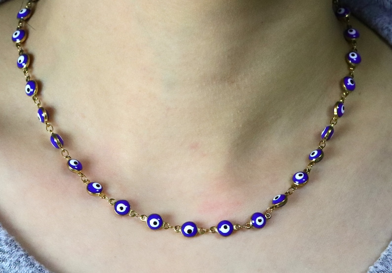 May include: A gold chain necklace with blue and white evil eye charms.