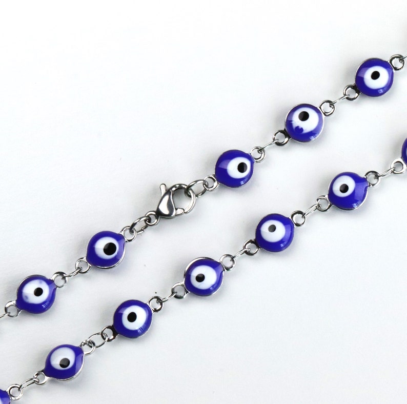 May include: A silver chain bracelet with blue and white evil eye charms. The bracelet has a lobster clasp closure.