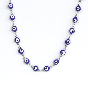 May include: A silver chain necklace with blue and white evil eye charms.