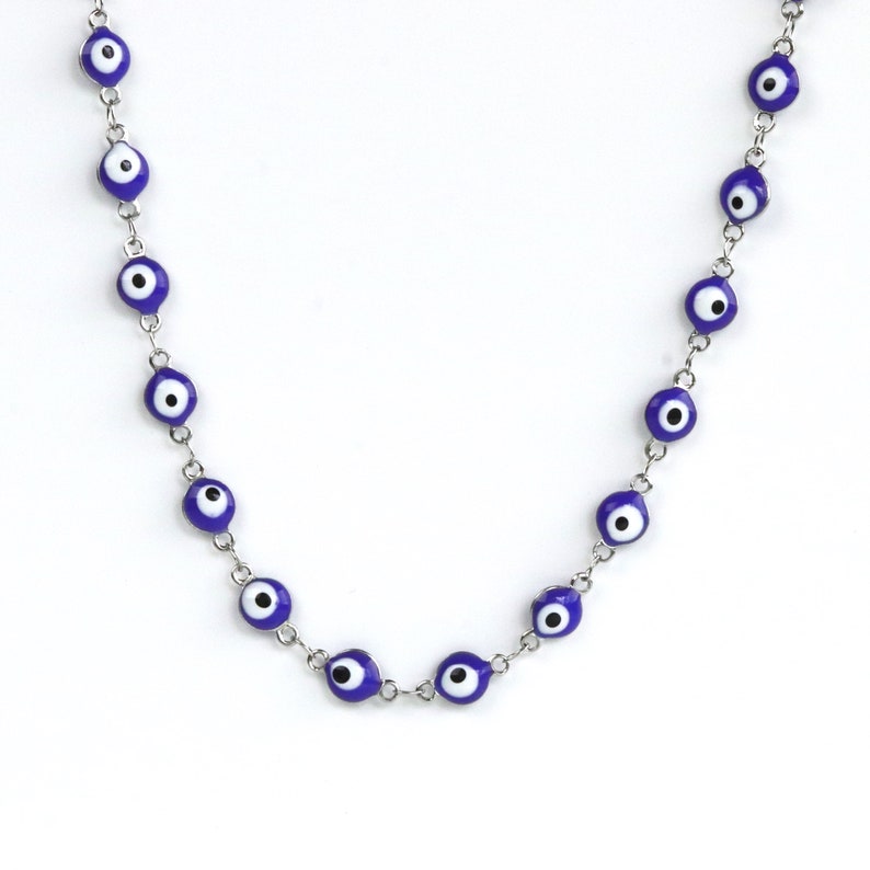 May include: A silver chain necklace with blue and white evil eye charms.