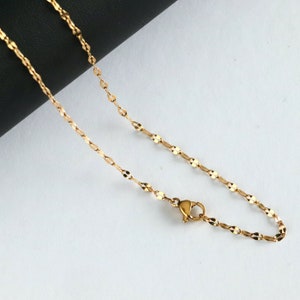 May include: A gold chain necklace with a lobster clasp closure. The chain is made of small, linked oval shapes.