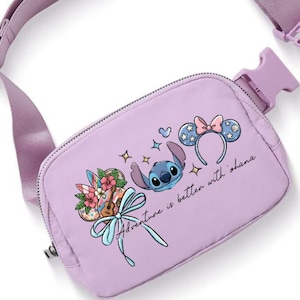 May include: A lavender fanny pack with a matching adjustable strap and buckle. The pack features a graphic of Stitch, floral elements, and the phrase "Adventure is better with ohana."