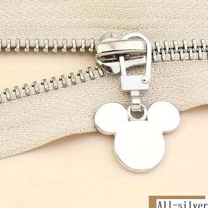 Op de afbeelding: Zilveren rits-trekker met een Mickey Mouse-kop ontwerp. De trekker is bevestigd aan een zilveren rits.