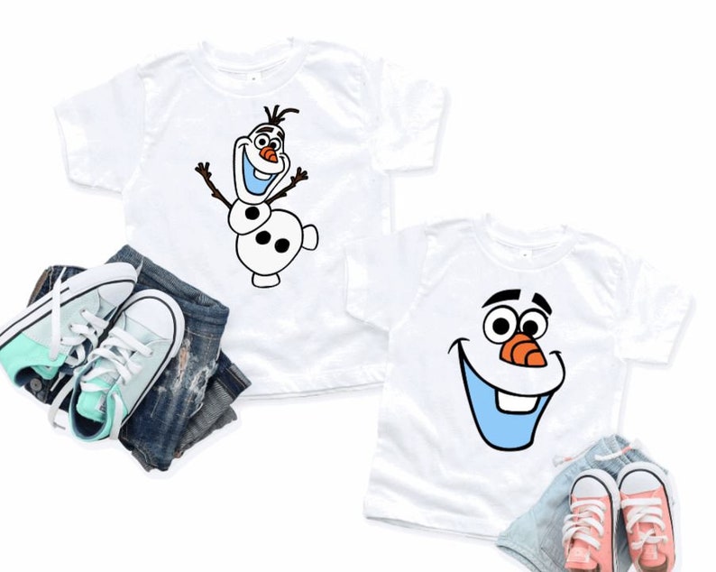 May include: Two white t-shirts featuring Olaf from Frozen. One shirt shows Olaf with arms raised, the other shows Olaf's face. The shirts are paired with denim shorts and sneakers in mint green and coral.