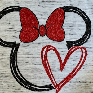 May include: A black and white outline of Mickey Mouse's head with a red glitter bow and a red glitter heart.