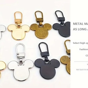 Op de afbeelding: Assortiment van zes metalen Mickey Mouse rits-trekkers in goud, zilver, zwart en brons. De rits-trekkers zijn gemaakt van duurzaam metaal en zijn niet gemakkelijk te roesten of te vervormen.