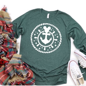 May include: A green long-sleeved t-shirt featuring a white anchor and Mickey Mouse head design. The design is within a circle with a rope border and stars.
