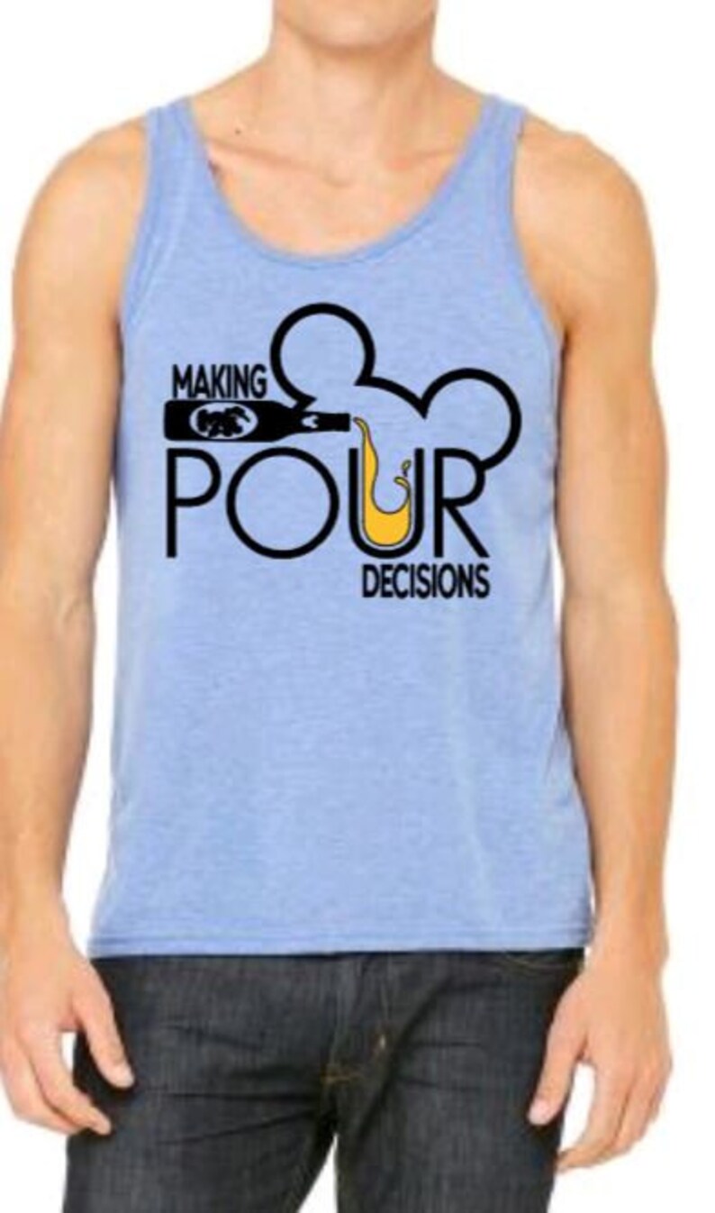 May include: Light blue tank top with the text "MAKING POUR DECISIONS" in black. The design includes a bottle pouring liquid into a Mickey Mouse-shaped outline. The tank top is worn with dark blue jeans.
