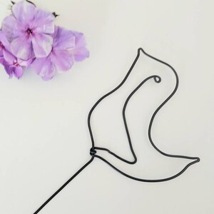May include: A black wire sculpture of a bird with a long, thin stem. The sculpture is on a white background.