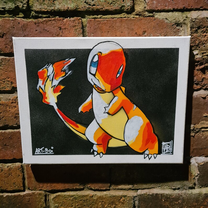 Puede incluir: Un lienzo pintado a mano con una ilustraci&oacute;n de dibujos animados de un Pok&eacute;mon de tipo fuego, Charmander, con un esquema de colores naranja brillante, amarillo y blanco sobre un fondo negro. La obra de arte est&aacute; firmada "ART-BOI" en la esquina inferior izquierda.
