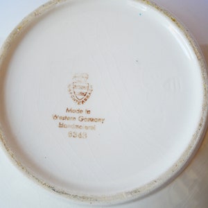 May include: White ceramic bowl with a brown stamp on the bottom that reads "Made in Western Germany Handgemalt 6349".