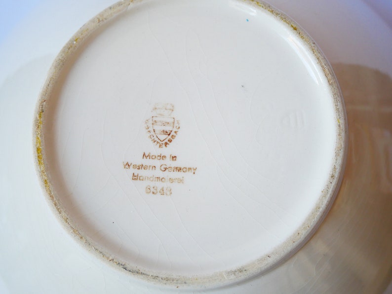 May include: White ceramic bowl with a brown stamp on the bottom that reads "Made in Western Germany Handgemalt 6349".