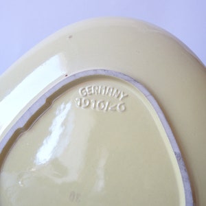 Op de afbeelding: Een gele keramische serveerschaal met een driehoekige stempel op de bodem met de tekst "GERMANY 1916126".