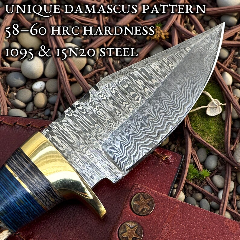 May include: Close-up of a Damascus steel knife with a unique pattern. The blade has a silver and gray design, with a brass bolster and a blue and black handle. The text on the image reads "UNIQUE DAMASCUS PATTERN" and "58-60 HRC HARDNESS".
