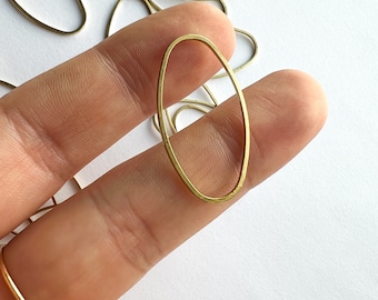 Può includere: Un primo piano di un anello di metallo ovale dorato. L'anello è liscio e ha una superficie leggermente testurizzata.