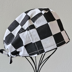 May include: Black and white checkered scrub hat with a tie string. The hat is made of a soft, comfortable fabric and is perfect for healthcare professionals.