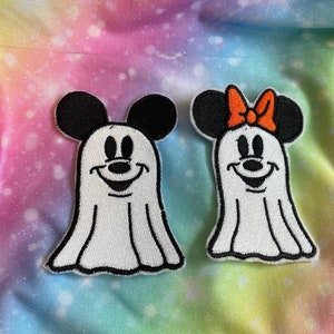 May include: Two white ghost-shaped embroidered patches with Mickey Mouse and Minnie Mouse faces. Mickey Mouse has black ears and Minnie Mouse has black ears with a red bow.