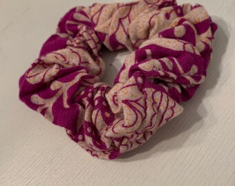 May include: A pink and white patterned scrunchie with a floral design.