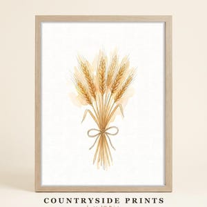 Peut inclure: Une impression murale encadrée représentant une illustration à l'aquarelle d'une gerbe de blé dorée nouée par un ruban. Le texte "COUNTRYSIDE PRINTS by 33rd St Prints" est imprimé en noir en bas. L'œuvre est dans un cadre en bois clair.