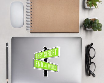 May include: A green and white street sign with the text "GREY STREET" and "END OF THE WORLD". The sign is on a silver laptop computer.