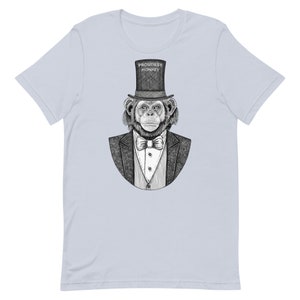 Peut inclure: Un t-shirt bleu clair avec une illustration en noir et blanc d'un chimpanzé portant un haut-de-forme et un nœud papillon. Le texte "PROUDEST MONKEY" est imprimé sur le haut-de-forme.