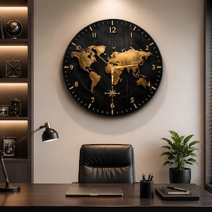 May include: A large circular wall clock featuring a black face with a gold-colored world map relief. The clock has gold-colored hour and minute hands, gold-colored numerals from 1 to 12, and a small compass rose design at the bottom center.