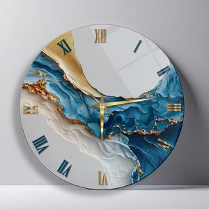 May include: A round wall clock featuring a fluid abstract design in shades of deep blue, white, and gold. The clock face displays Roman numerals in blue and gold, with thin gold-colored hour, minute, and second hands centered on the dial.