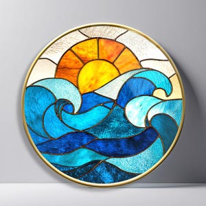 May include: A circular stained glass panel featuring a vibrant yellow and orange sun rising above stylized ocean waves in various shades of blue. The piece is encased in a thin gold-toned metal frame, with distinct dark lead lines separating each glass segment.