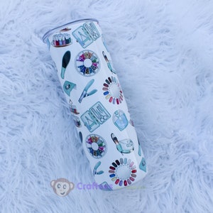 Könnte beinhalten: Ein weißer Edelstahlbecher mit einem bunten Design aus Nagelstudio-Werkzeugen und -Utensilien. Der Becher hat einen Deckel und fasst etwa 20 Unzen.