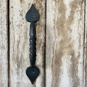 May include: Black metal door handle with a twisted design and heart-shaped ends.
