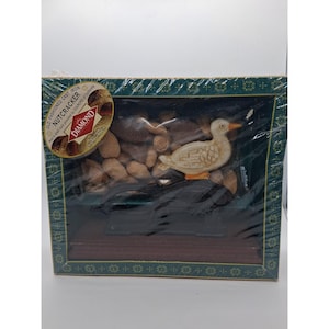 Puede incluir: Un juego de cascanueces de hierro fundido vintage en una caja de presentación. La caja presenta una figura de pato y una colección de nueces. El embalaje incluye el texto "OLD FASHIONED CAST IRON NUTCRACKER" y el logotipo de la marca Diamond.