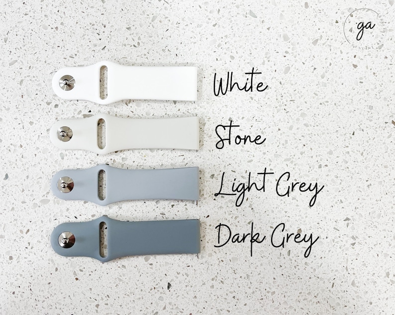 Pu&ograve; includere: Quattro cinturini per orologi bianchi, pietra, grigio chiaro e grigio scuro. Ogni cinturino ha una chiusura color argento. I colori sono etichettati con testo scritto a mano: Bianco, Pietra, Grigio chiaro e Grigio scuro.