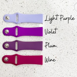 Pu&ograve; includere: Quattro cinturini colorati per orologi in tonalit&agrave; viola e rosa sono esposti su uno sfondo bianco maculato. I colori sono viola chiaro, viola, prugna e vino. Il testo sull'immagine indica i nomi dei colori.