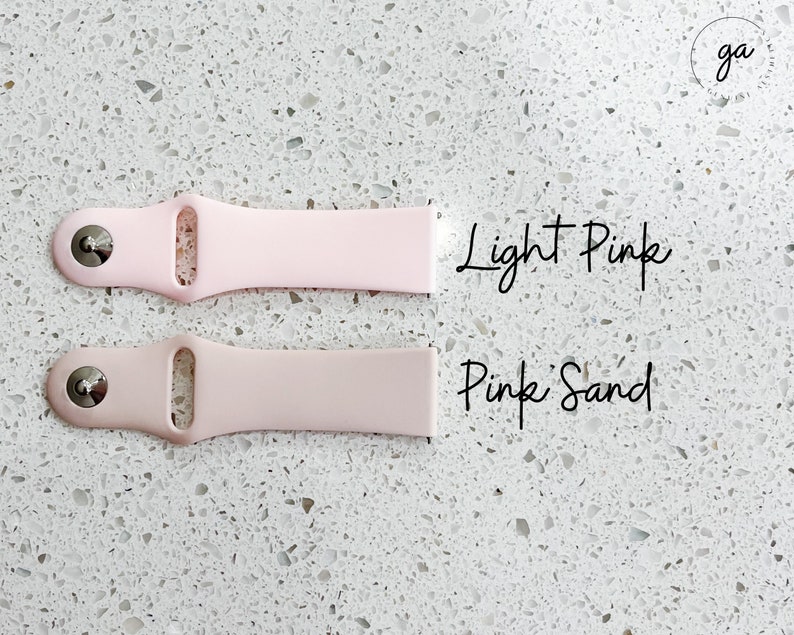 Pu&ograve; includere: Due cinturini per orologi in silicone rosa chiaro e rosa sabbia. Il cinturino rosa chiaro &egrave; in alto e quello rosa sabbia sotto. Il testo "Light Pink" e "Pink Sand" &egrave; scritto in corsivo accanto a ciascun cinturino.