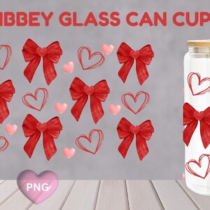 May include: A 16 oz glass can cup wrap with a red and white design featuring red bows and pink hearts. The wrap is shown on a glass jar with a wooden lid.