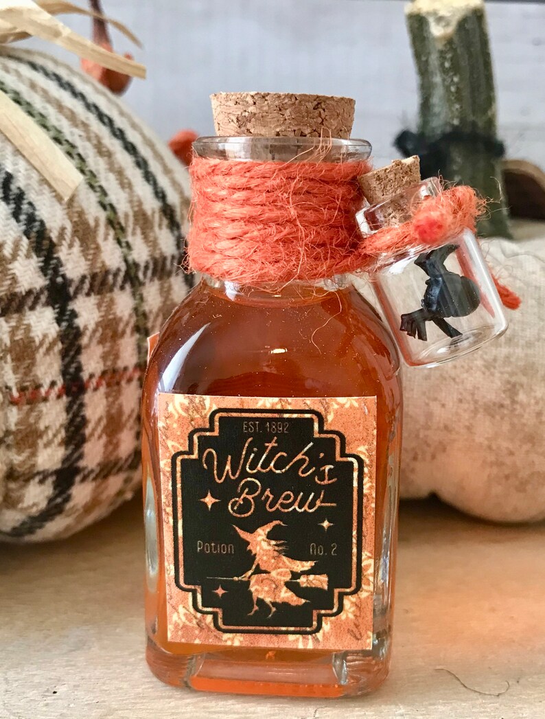 Pu&ograve; includere: Una piccola bottiglia di vetro con un tappo di sughero e un'etichetta che recita "Witch's Brew Potion No. 2" con una strega che vola su una scopa. La bottiglia &egrave; legata con uno spago arancione e ha una bottiglia di vetro pi&ugrave; piccola con un corvo nero all'interno che pende dal collo.