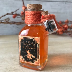 Pu&ograve; includere: Una piccola bottiglia di vetro con un tappo di sughero e un'etichetta che recita "Witch's Brew Potion No. 2". La bottiglia &egrave; piena di un liquido arancione scuro ed &egrave; legata con uno spago arancione. Un piccolo flacone di vetro con un ragno nero all'interno &egrave; attaccato alla bottiglia.