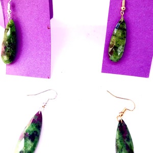 May include: A pair of earrings with green and pink gemstone drops. The earrings have gold and silver hooks.