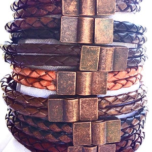 May include: A stack of braided leather bracelets with antique brass clasps. The bracelets are in shades of brown and tan.