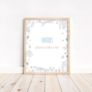 May include: A white sign with a wooden frame and a blue and pink border. The sign says "Favors please take one" and is decorated with illustrations of clothing, hearts, and stars.