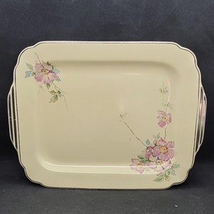 May include: A white rectangular serving tray with a gold rim and a floral design featuring pink flowers and green leaves.