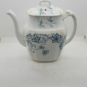 May include: White teapot with a blue floral design. The teapot has a lid with a small knob on top. The teapot is made of ceramic and has a classic design.