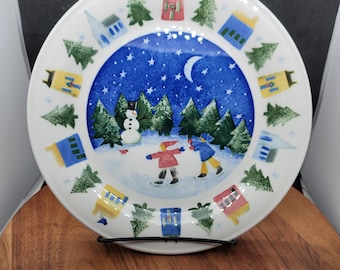 Set di due (2) piatti piani Nikko Winter Wonderland, scena di pattinaggio al centro, case e alberi sempreverdi sul bordo, Deb Mores, 10,75" (3246)