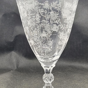以下が含まれることがあります： 花柄のエッチングが施された透明なガラスのゴブレット。ゴブレットは、幅広のフレアボウル、装飾的なステム、丸いベースを備えています。エッチングパターンは花と葉で構成されています。ガラスは透明です。